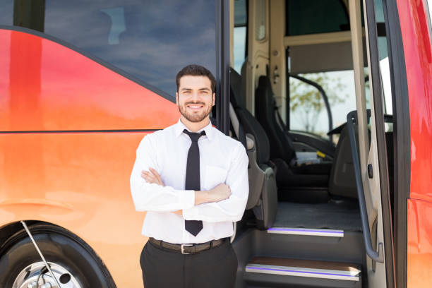 Portrait of good looking driver standing arms crossed outside intercity bus